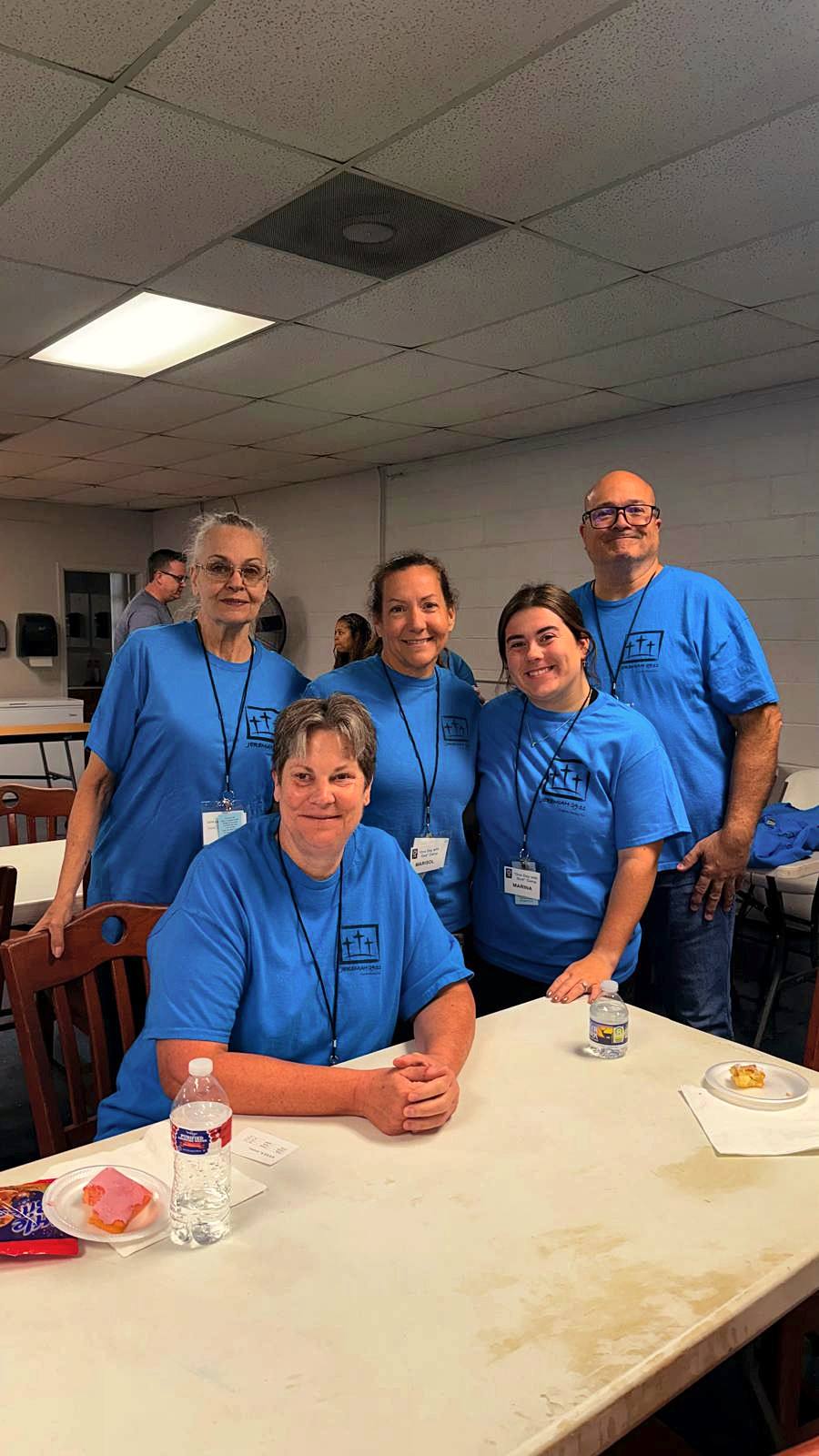 Volunteers in blue camp shirts gathered at a table