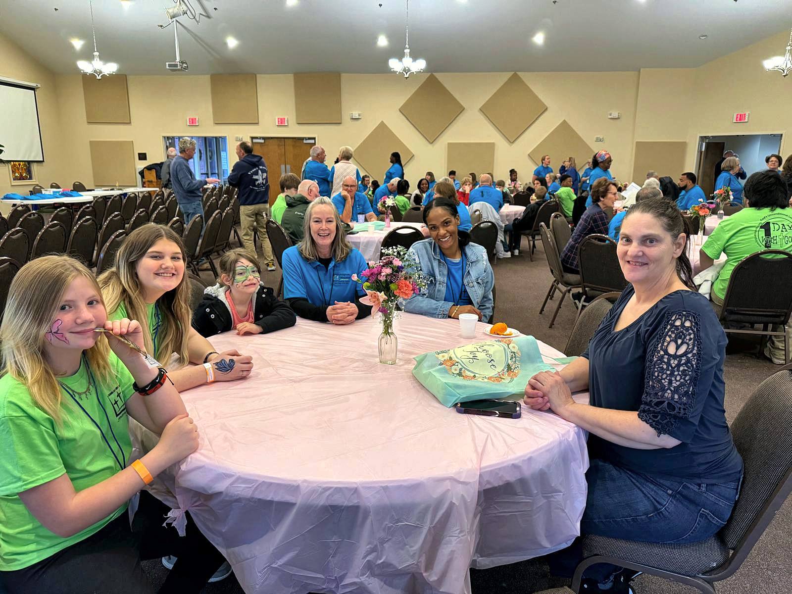 Girls and volunteers smiling around a table with flowers