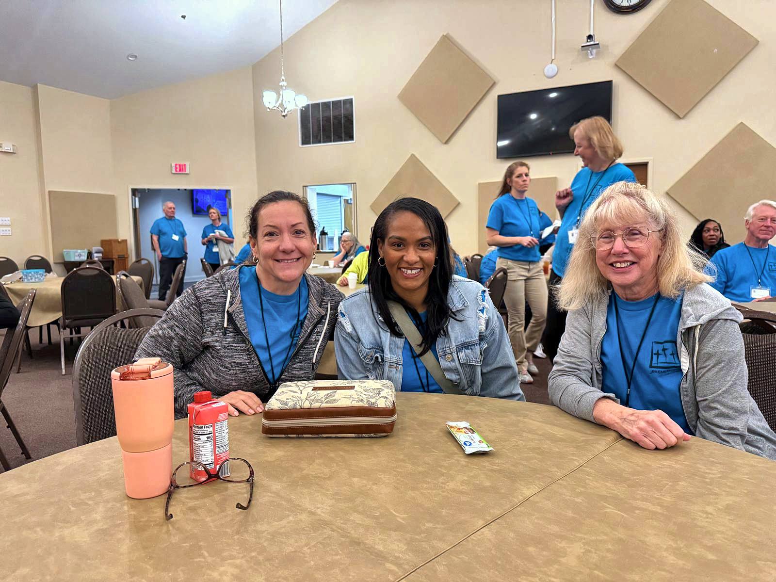 Three volunteers smiling at a round table