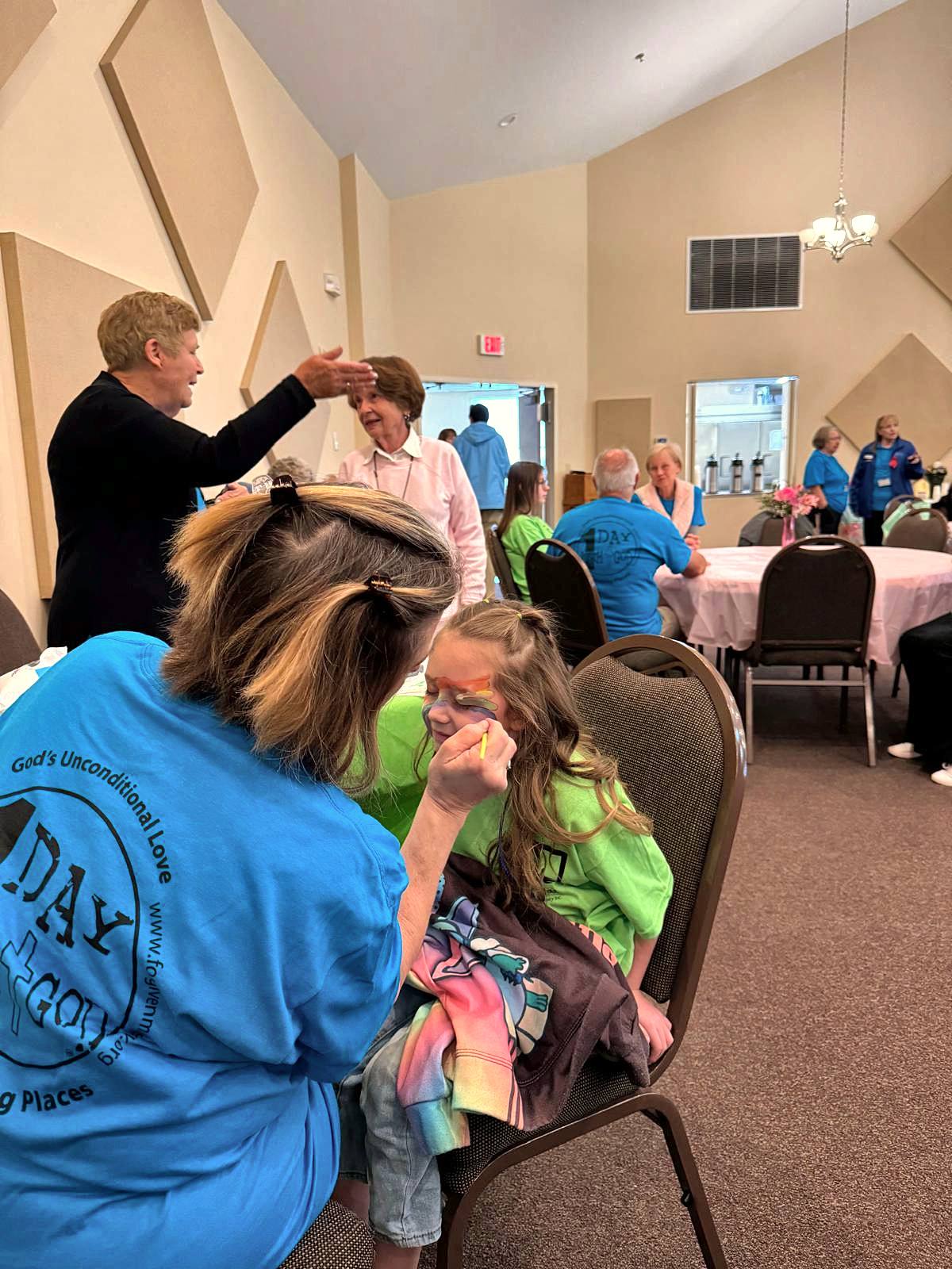 A volunteer painting a girl’s face