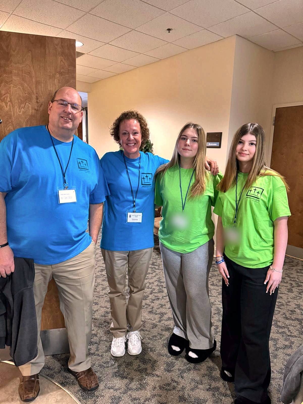 Two volunteers in blue camp shirts with two teenage girls