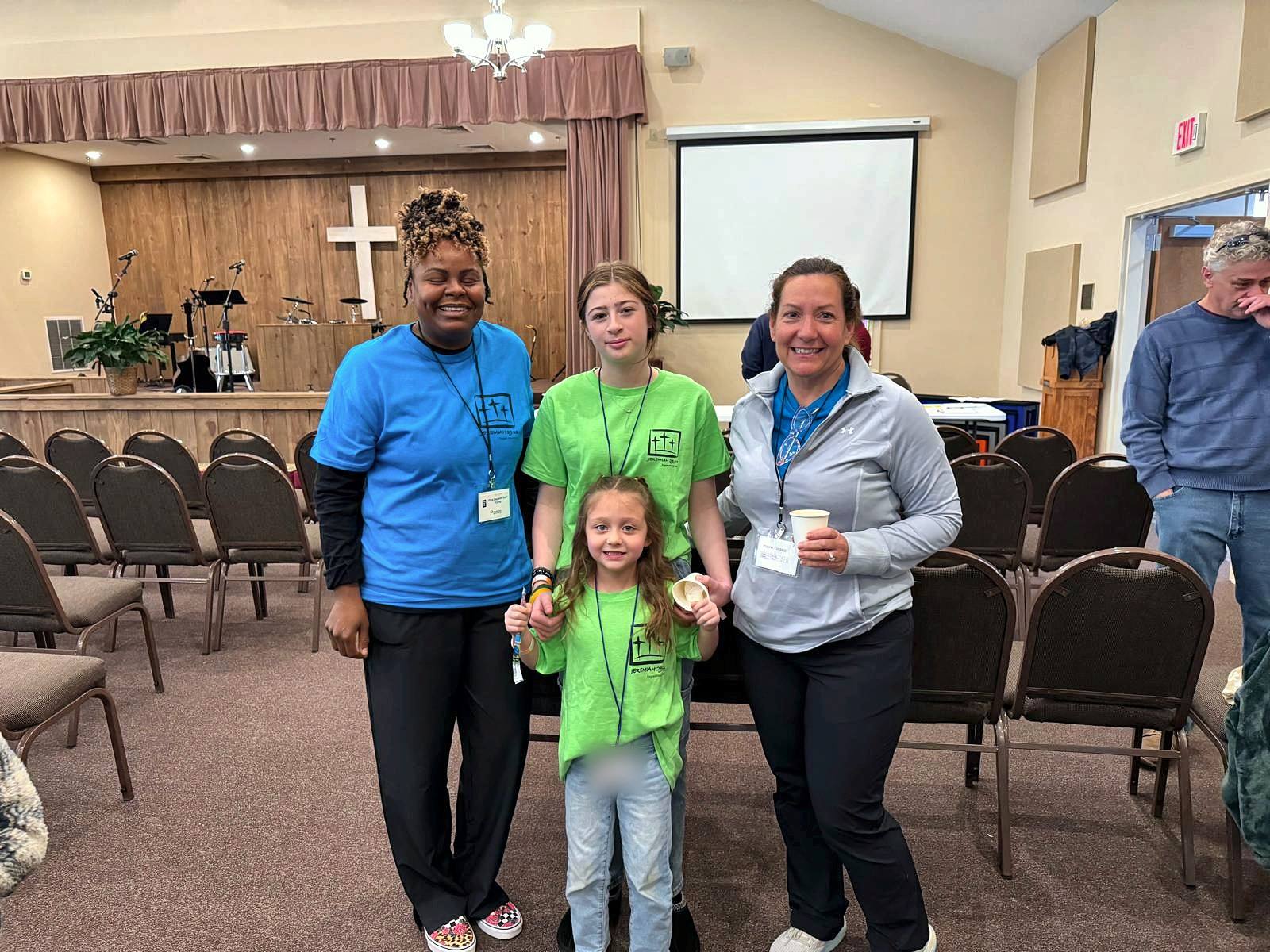 Two volunteers with two girls in green camp shirts