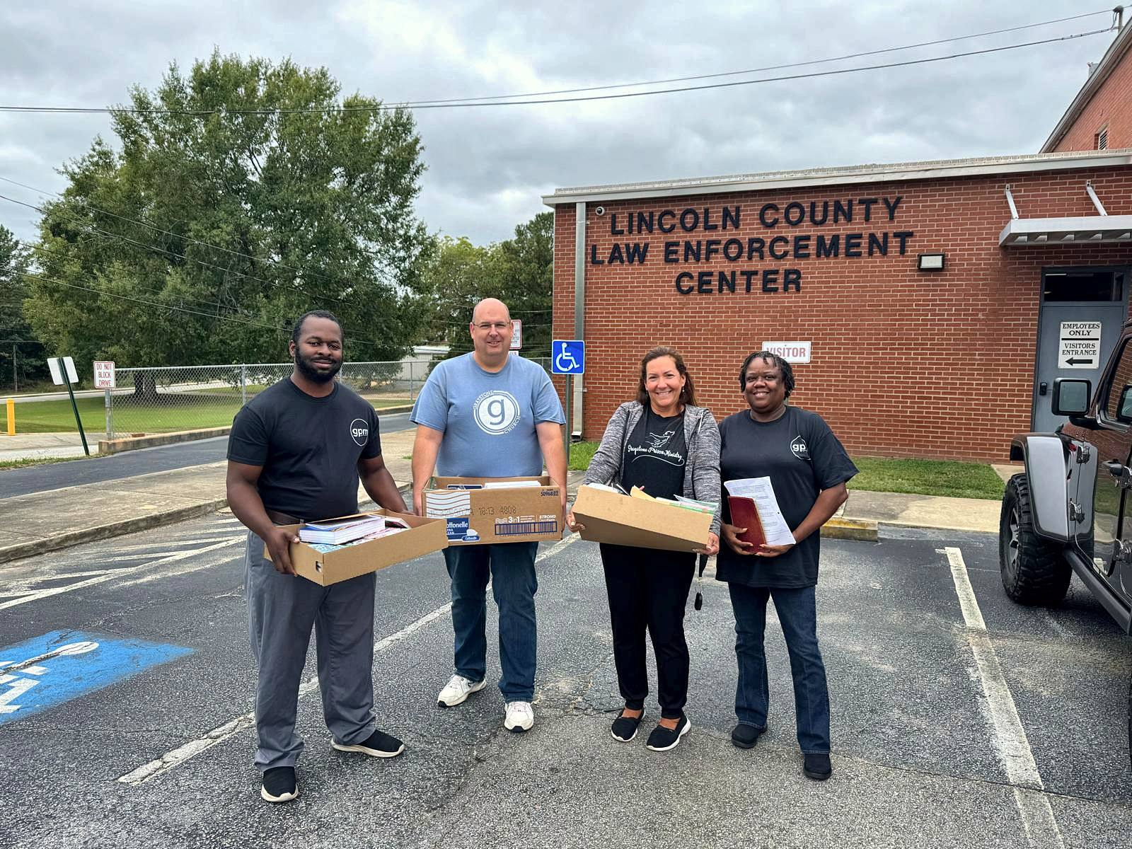 Four volunteers carrying boxes across the jail parking lot