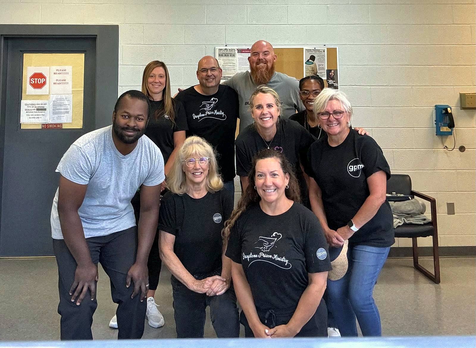 Volunteers in GPM shirts smiling in the jail lobby