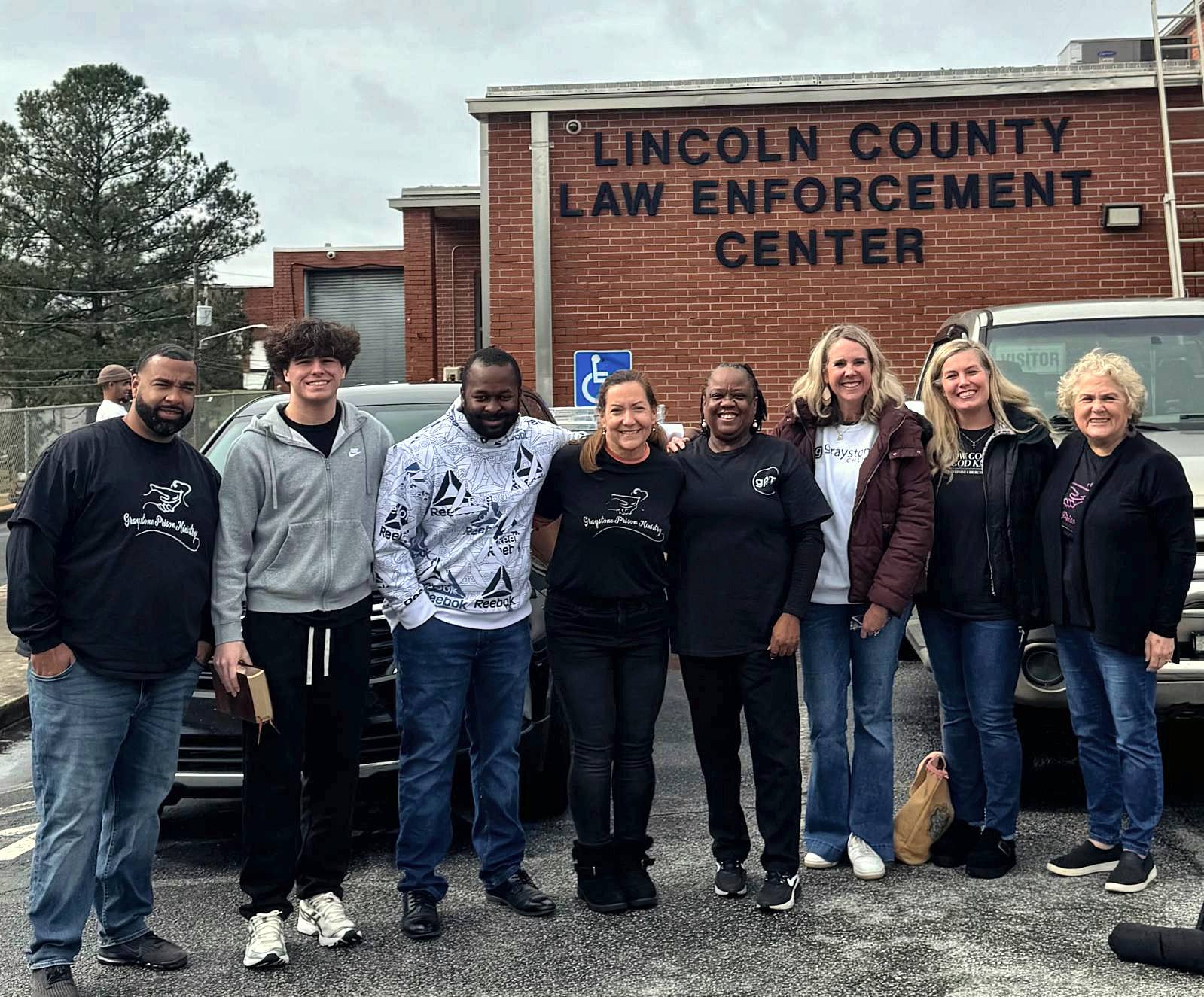 A large group of volunteers in front of the Lincoln County Law Enforcement Center sign
