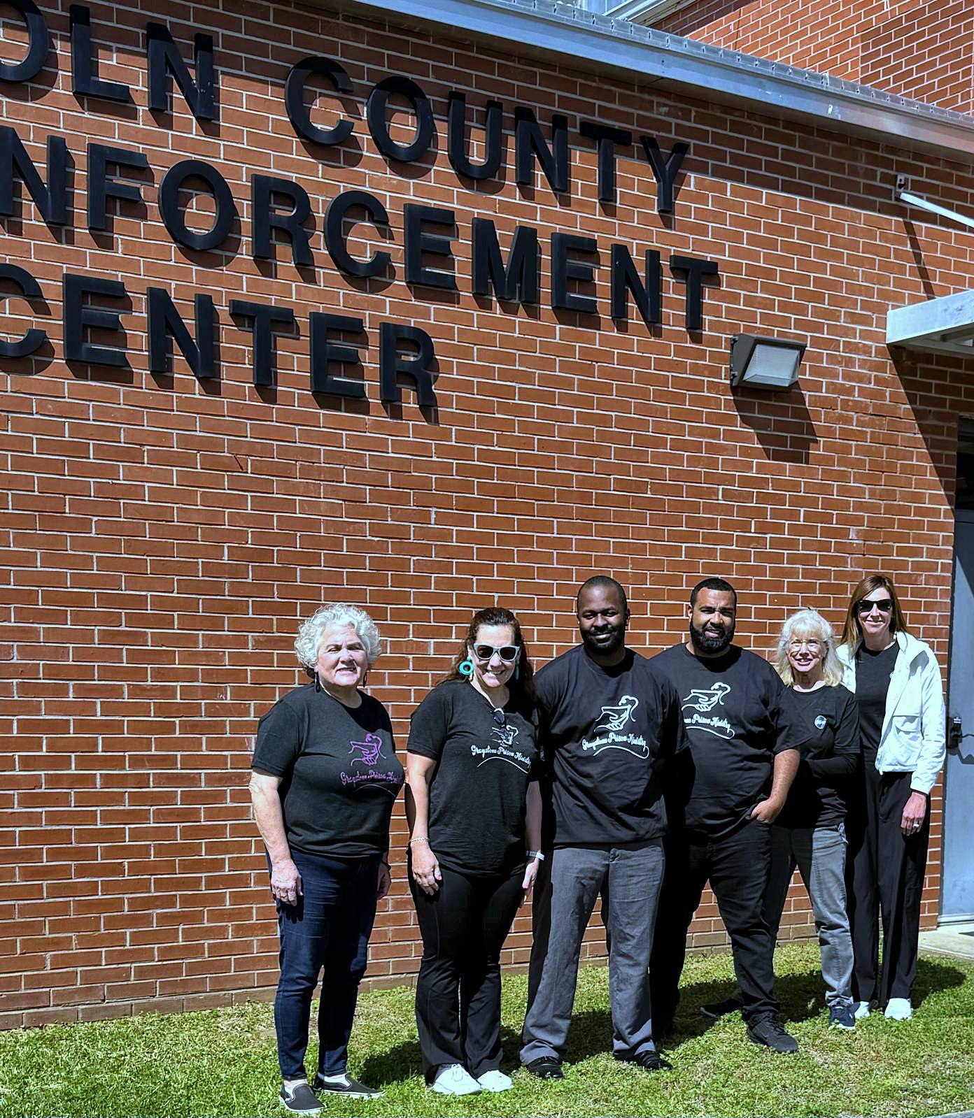 A small group of volunteers in front of the jail building