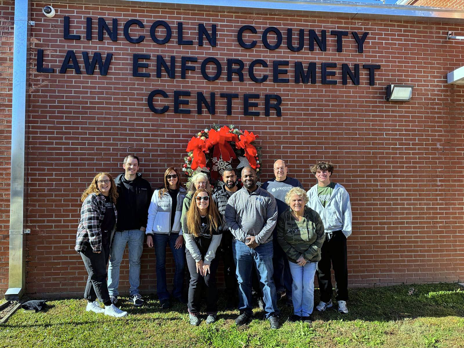 The GPM team under a Christmas wreath on the Lincoln County Law Enforcement Center