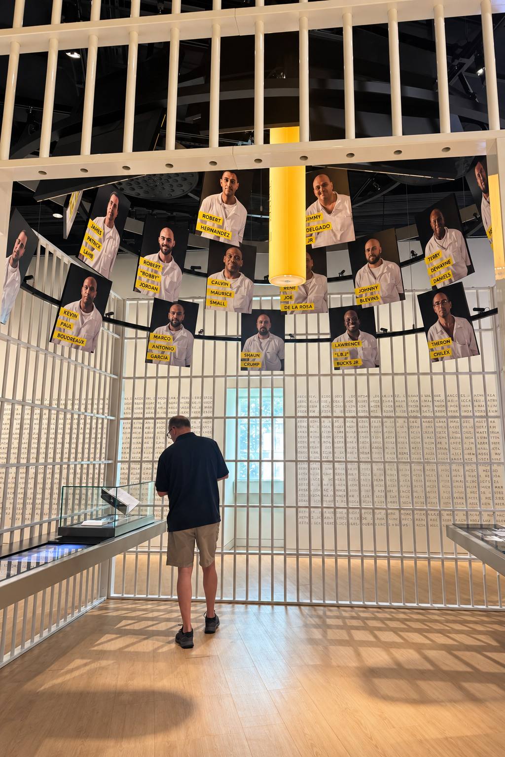 A museum exhibit built from prison bars, with portraits of graduates hanging above