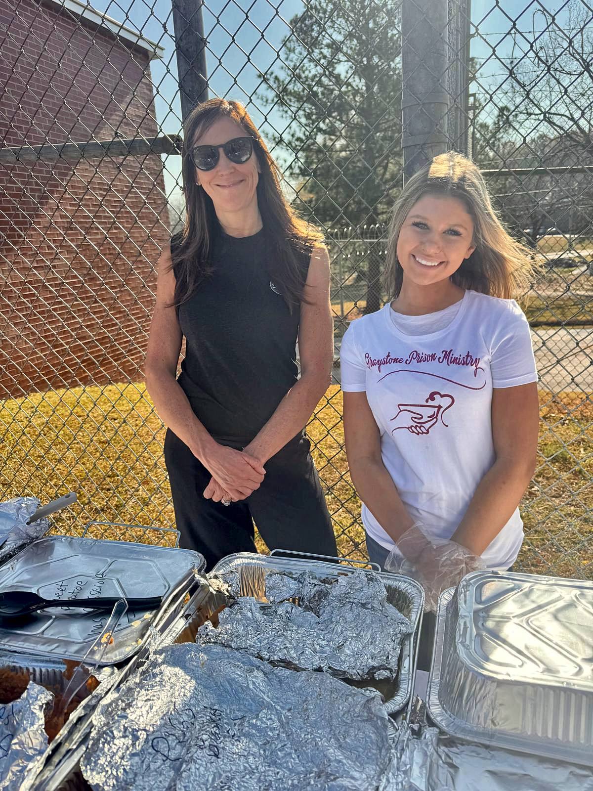 Two young volunteers smiling behind the serving table